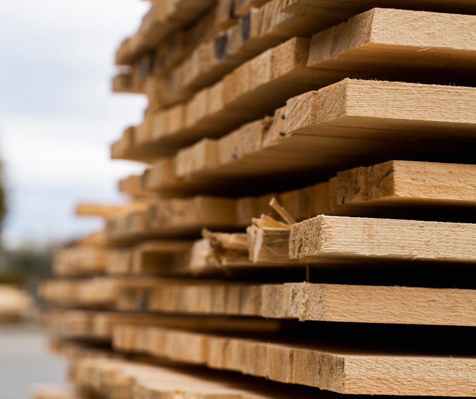 Stack of freshly sawn lumber boards in a log yard — typical output of Quebec sawmills serviced by CFI Industries in Saguenay–Lac-Saint-Jean, Mauricie and the North Shore.
