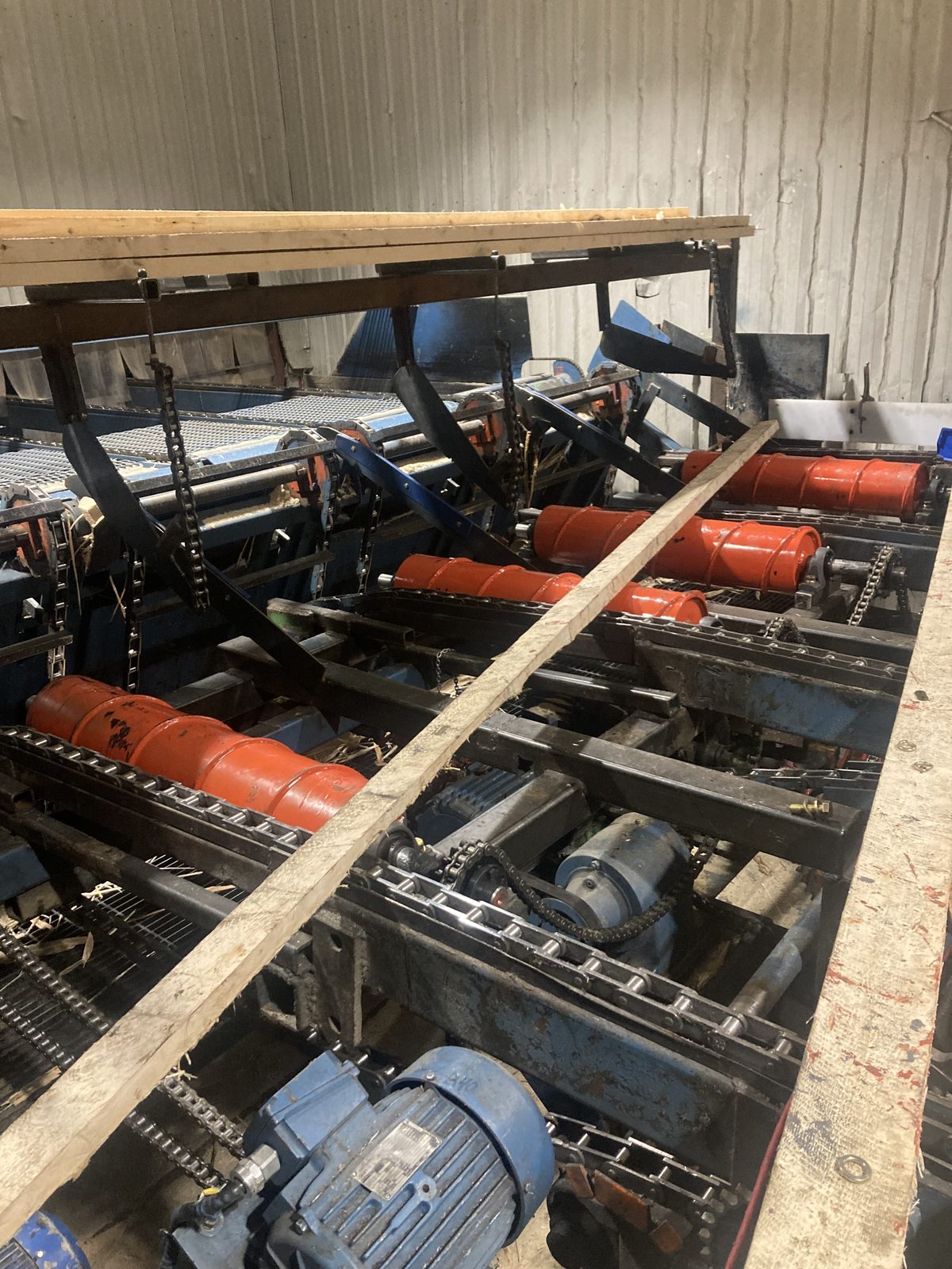Convoyeur à chaîne de scierie avec rouleaux centreurs orange neufs fabriqués sur mesure par CFI Industrie pour la scierie d'Opitciwan en Mauricie