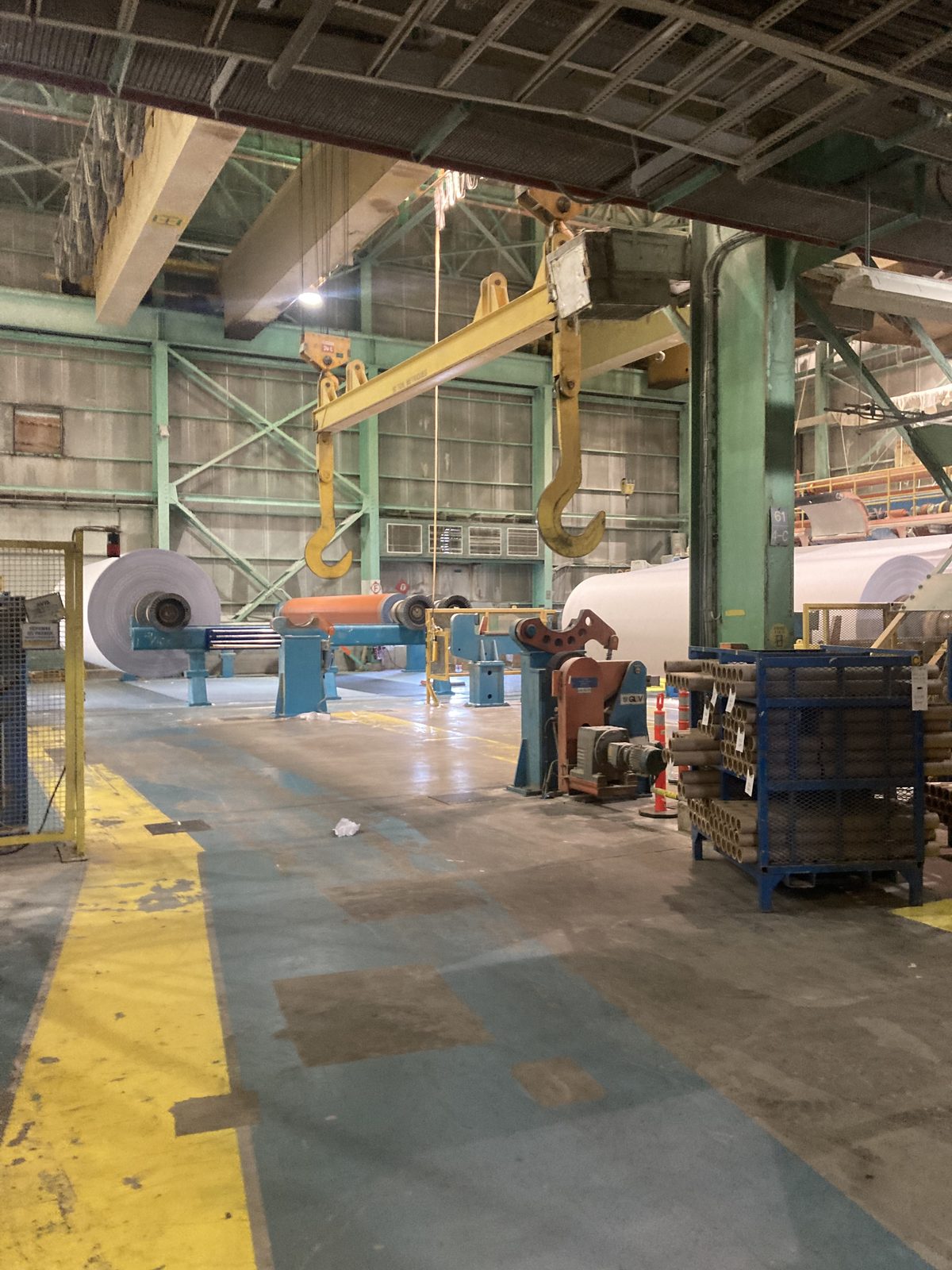 Interior of Resolute paper mill with paper rolls and overhead crane lifting system — paper machine modification by CFI Industries in Quebec